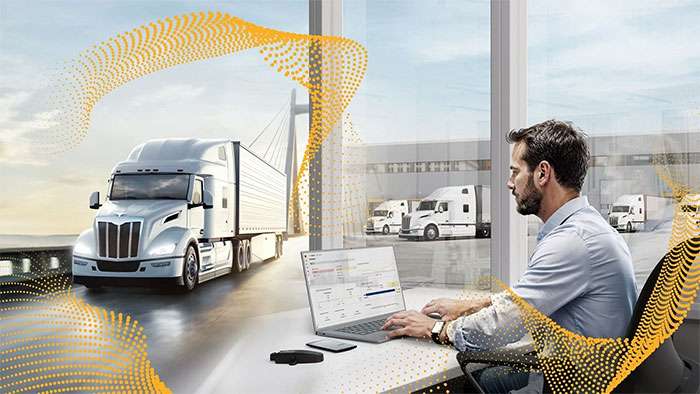 Office laptop with trucks outside illustrating Continental and Samsara digital tire monitoring integration.