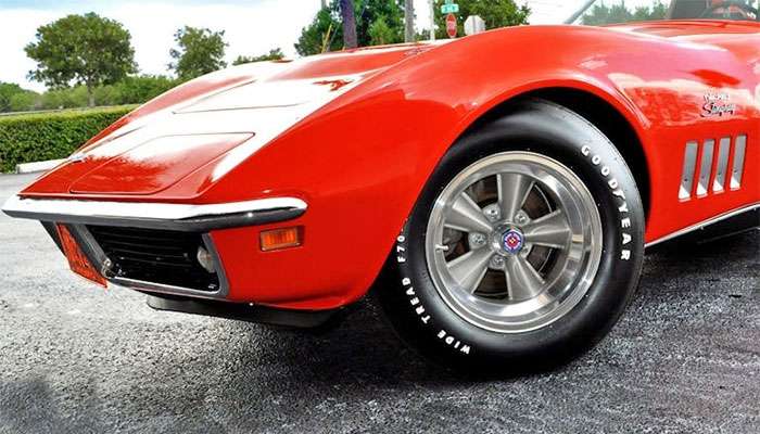 Close-up of a red Chevrolet Corvette with Torq Thrust wheels and Goodyear tires on a paved surface.