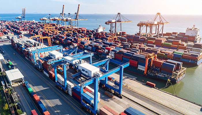 Aerial view of a crowded shipping port with numerous containers and cranes illustrating global supply chain disruptions.