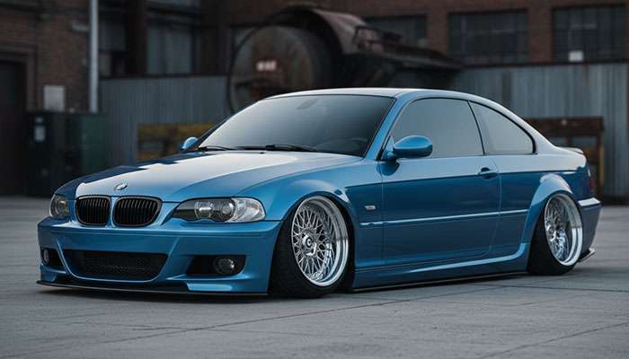 Blue BMW coupe with aggressive lowered stance and deep-dish mesh wheels parked in an industrial area