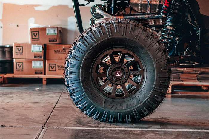 Close-up of a DOT approved Valor Offroad UTV tire mounted on a vehicle in a warehouse setting.