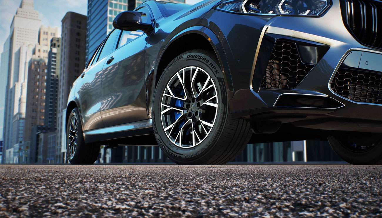 Close-up of a car's Hankook tire and alloy wheel on a wet road, highlighting tire brand and tread details