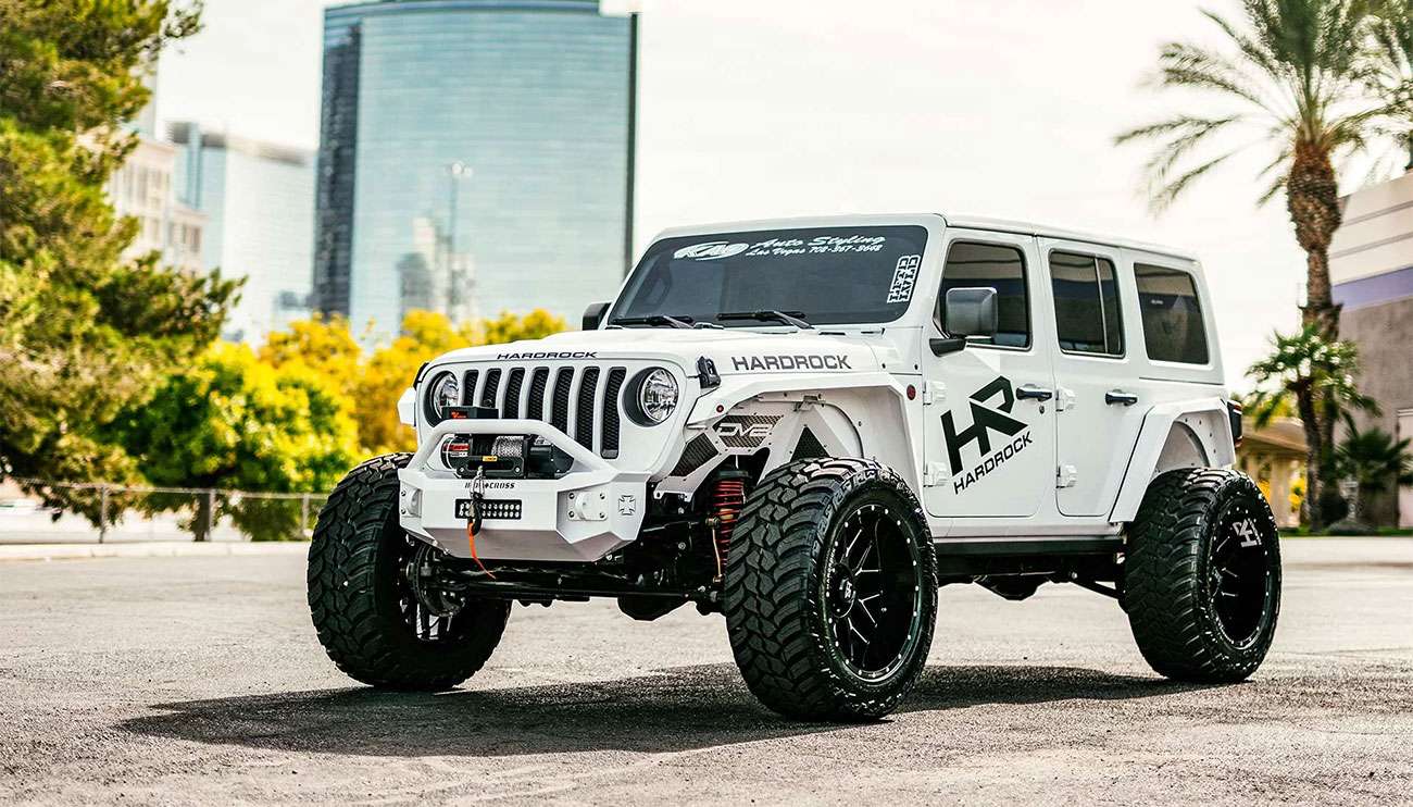 Close-up of a black truck fitted with rugged Hardrock off-road wheels and tires at sunset