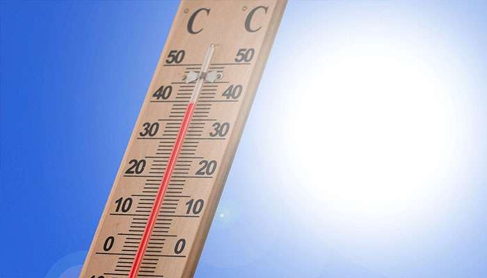 Close-up of a thermometer showing high temperature against a bright sunny blue sky background.