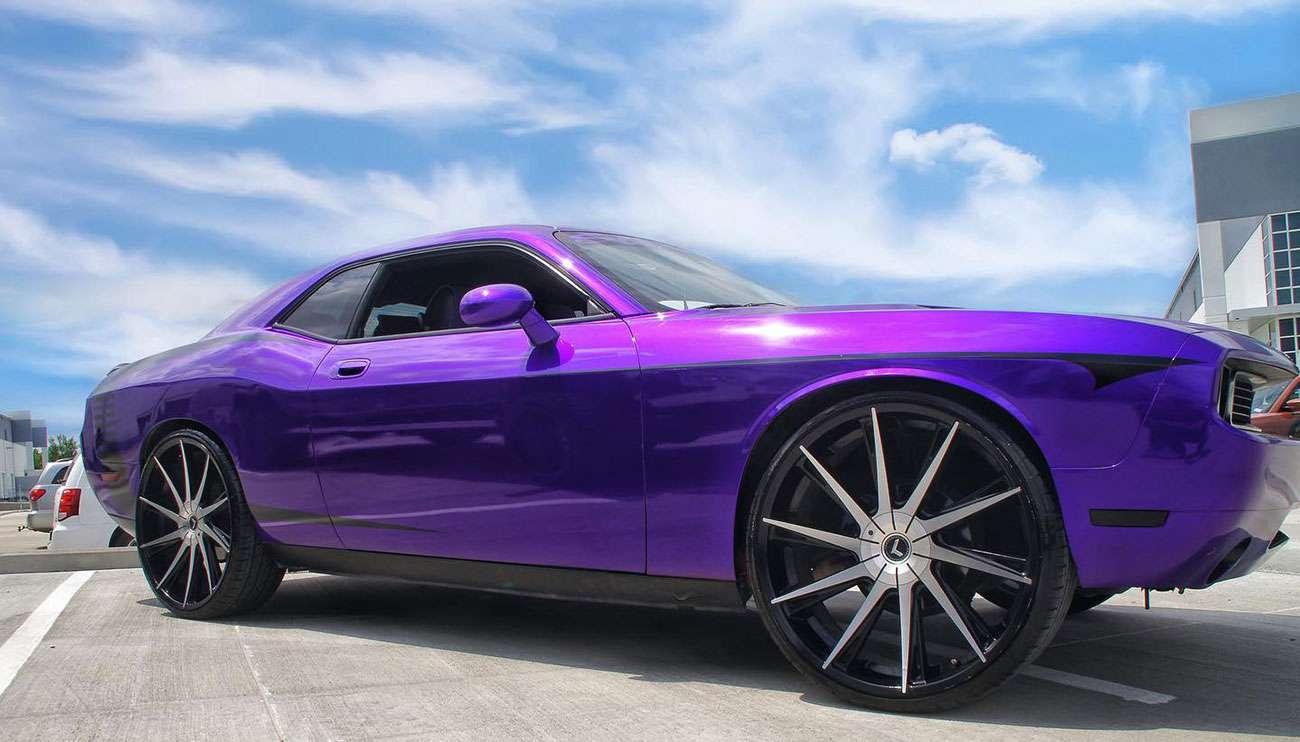 Close-up of shiny black and chrome Kraze custom car rims lined up in warehouse with shelves and boxes in background