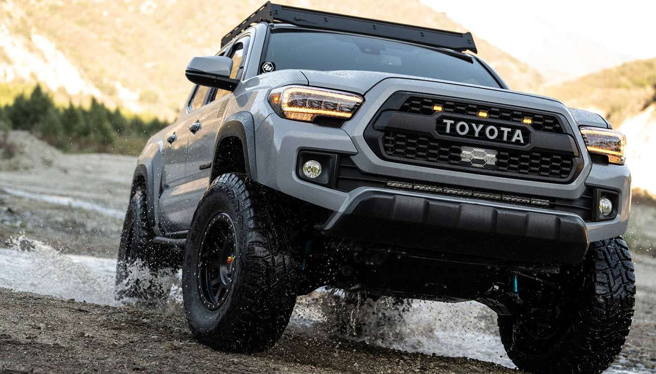Close-up of a rugged Method off-road wheel and tire on a vehicle driving over desert sand at sunset