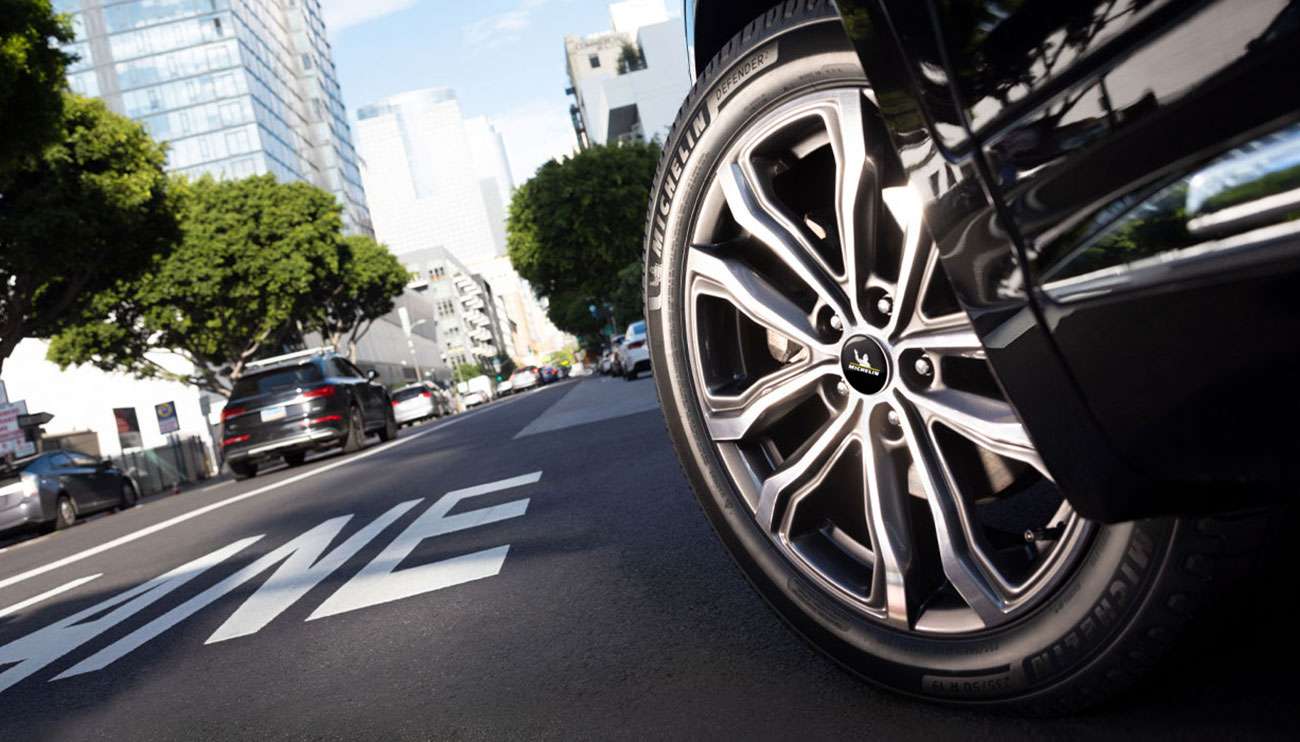 Close-up of a black car with Michelin Defender 2 tires on a smooth road, highlighting tire performance and design