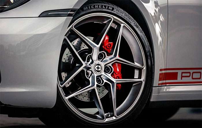 Close-up of a modern car rim with a Michelin tire and red brake calipers on a white sports car