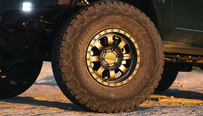 Beadlock wheel in matte black with bronze accents, displayed with a tire mounted