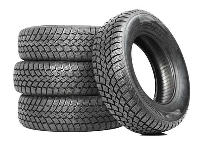 Stack of four all-season tires with detailed tread patterns designed for electric vehicle performance.
