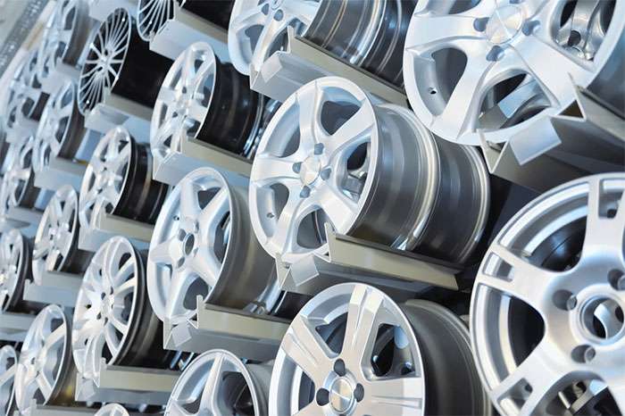 Stacked aluminum alloy wheels showcasing various designs in a manufacturing or storage facility