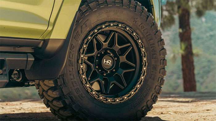 Black steel off-road wheel on rugged pickup truck with rocks in foreground