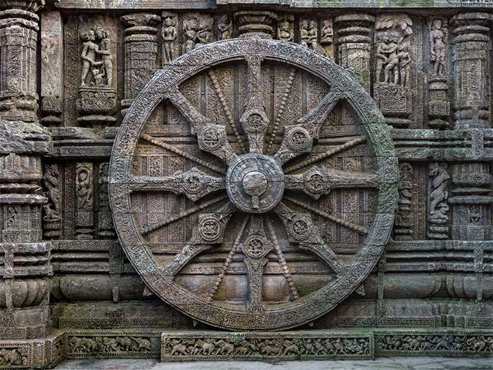 Intricately carved stone wheel on an ancient temple wall, showcasing detailed historic craftsmanship and symbolism.