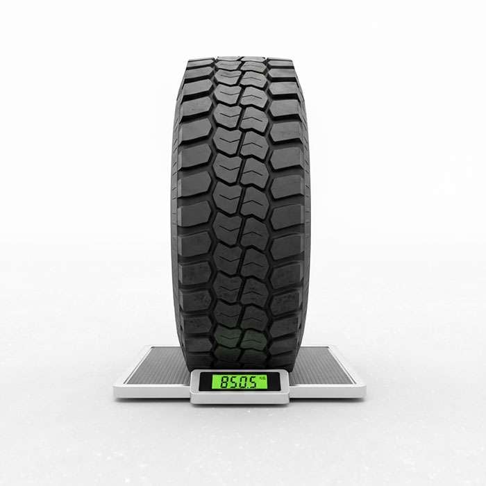 Truck tire on a digital wheel pad scale displaying weight measurement on asphalt surface