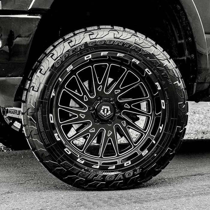 Close-up of black and chrome TIS 544BM custom 20x12 wheel with exposed lugs and detailed spoke design
