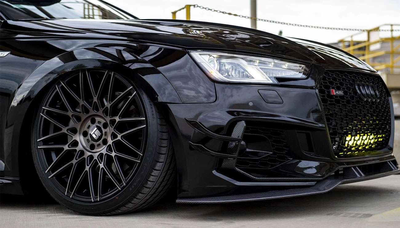 Sleek black sports car with illuminated headlights and stylish alloy wheels in a modern showroom