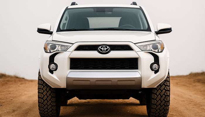 Front view of a white Toyota SUV equipped with Cooper Evolution M/T mud terrain tires on a dirt road