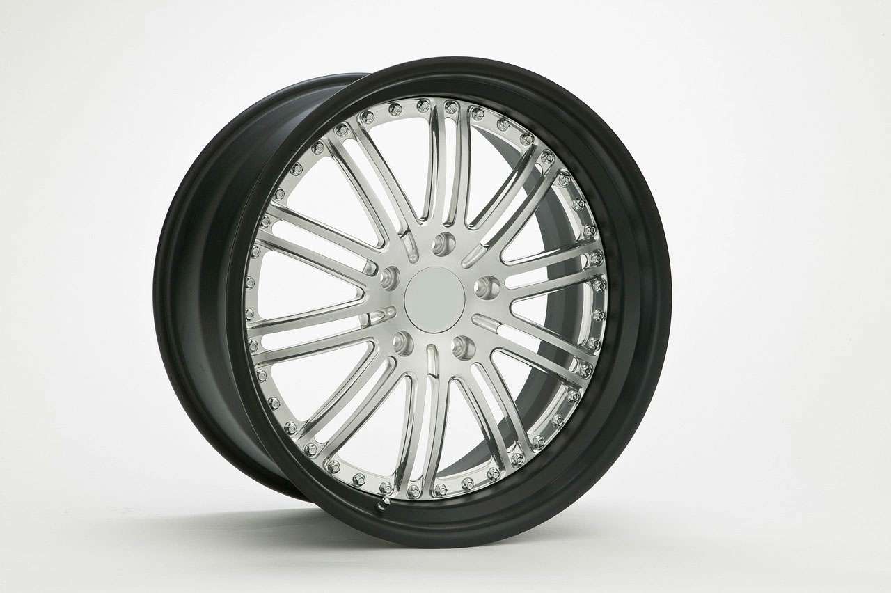 Close-up of a shiny silver car wheel rim with black tire against a white background.