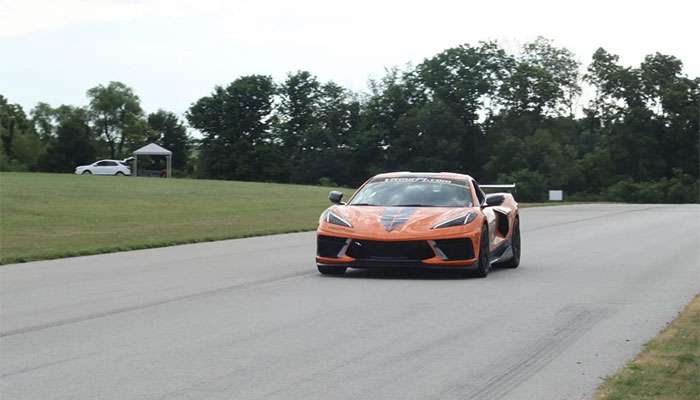 Orange sports car driving on a wet road course during a rain test.