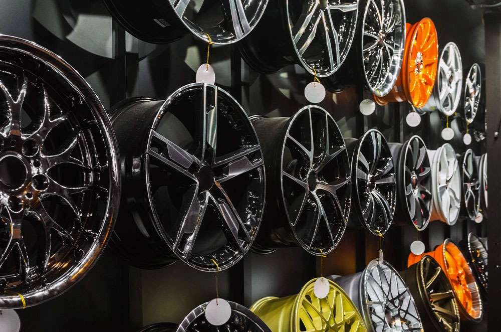 Various styles and colors of car wheels displayed on a wall in a showroom or store setting.