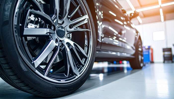 Closeup of premium chrome wheels and tires on a modern vehicle inside a service shop.