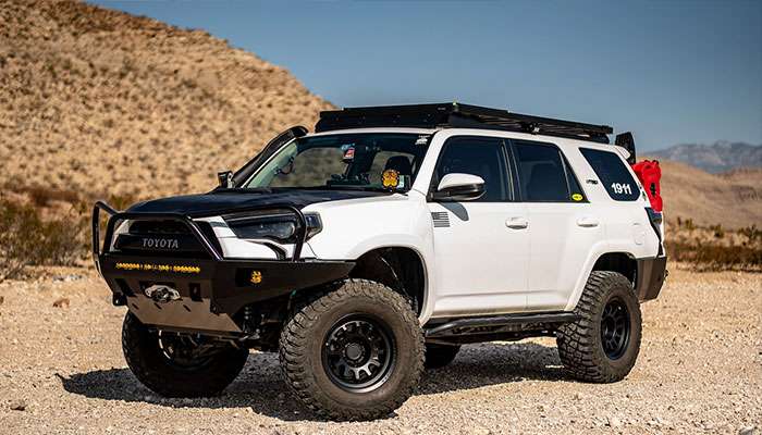 2021 white Toyota 4Runner equipped with Black Rhino RAPID black wheels and off-road accessories in desert landscape