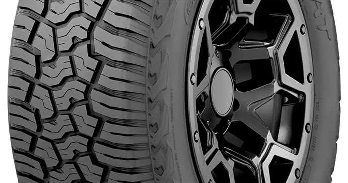 Yokohama Geolandar X-AT tire on dirt and gravel road, showing dual sidewall design.
